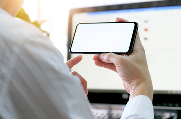 Wall Mural - man using smartphone while sitting in modern office, blank screen of phone.