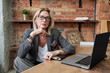© pressmaster - Portrait of serious fashionable mature business lady in jacket sitting at desk with open laptop in own office
