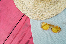 Cut View Of Pink And Blue Towels Or Blankets Lying On Each Other. Yellow Sunglasses And Piece Of Big Straw Hat. Preparation For Vacation. Summertime.