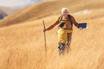 Wall Mural - Senior man with grandson on country walk in autumn.