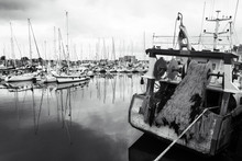 Fishing Ship And Sailing Boats At Harbor In Cloudy Day. Normandy, France. Fishing Industry And Leisure Sailing Tourism Concept. Nautical Background. Black White Photo.