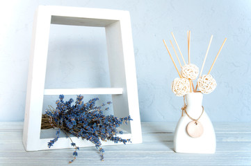 Blue flowers on the table. White frame. Wood background. Vase with aromatic sticks. Still life