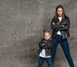 © FAB.1 - Positive young woman and little girl in similar jeans and black leather jackets standing in same pose over concrete background