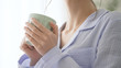 © aijiro - パジャマ姿でマグカップを持つ女性