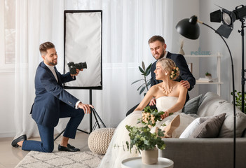 Wall Mural - Photographer working with young wedding couple in studio