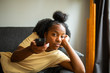 bored african american girl on sofa pointing tv remote control