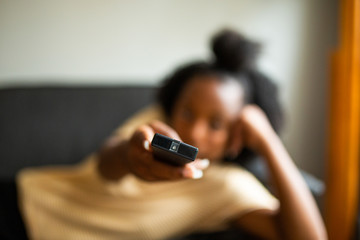 Wall Mural - Close up african american girl relaxing with tv remote control