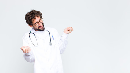 Canvas Print - young doctor man smiling, feeling carefree, relaxed and happy, dancing and listening to music, having fun at a party against copy space wall