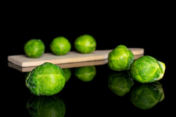 Sticker - Group of six whole fresh green brussels sprout on small wooden cutting board isolated on black glass