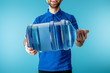 Cropped view of smiling courier holding bottled water isolated on blue