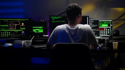 Caucasian young male virtual spy hacking some software at night in the dark room