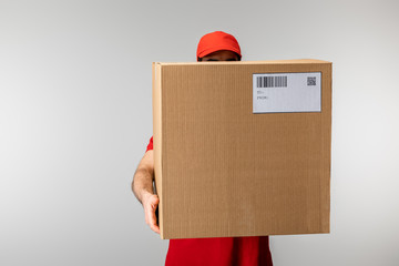 Courier in cap holding box with barcode and qr code on card isolated on grey