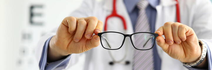 Wall Mural - Male medicine doctor hands giving pair of black glasses