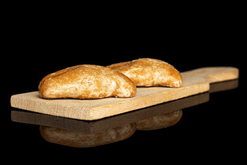 Group of two whole sweet brown gingerbread on small wooden cutting board isolated on black glass