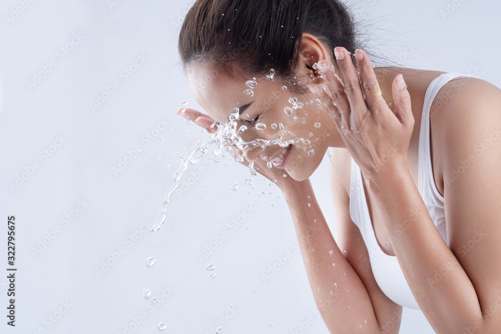 Beautiful woman washing her face in a white background studio - obrazy, fototapety, plakaty 