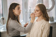 © Aleksandr - Makeup artist work in her beauty studio. Portrait of Woman applying by professional make up master. Beautiful make up artist start making a makeup for blond hair model