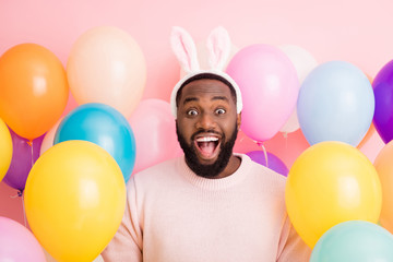 Photo of funny dark skin guy colorful decorations easter party festive mood open mouth wear sweater fluffy bunny ears on balloons pink color background