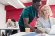 © Sam Edwards/Caia Image - Teacher helping community college student at desk in classroom