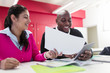 © Sam Edwards/Caia Image - Smiling community college students with paperwork and digital tablet