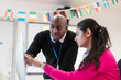 © Sam Edwards/Caia Image - Community college instructor helping student at computer in classroom