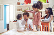 © Trevor Adeline/Caia Image - Young family playing with toy dinosaurs in kitchen