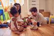 © Trevor Adeline/Caia Image - Young family playing with toys on floor