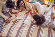 © Trevor Adeline/Caia Image - Young family coloring on bed