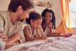 © Trevor Adeline/Caia Image - Young family coloring on bed