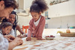 © Trevor Adeline/Caia Image - Young family playing scrabble word game at table