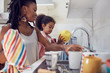 © Trevor Adeline/Caia Image - Mother and daughter washing dishes at kitchen sink