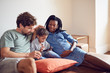 © Trevor Adeline/Caia Image - Young pregnant family using smart phone on living room sofa