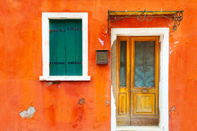 Window With Shutters And Door On The Orange Facade Of The House. Colorful Architecture In Burano Island, Venice, Italy.