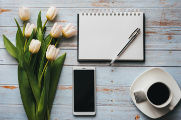 Wall Mural - White bouquet of tulips on wooden background with coffee Cup, smartphone and empty notebook