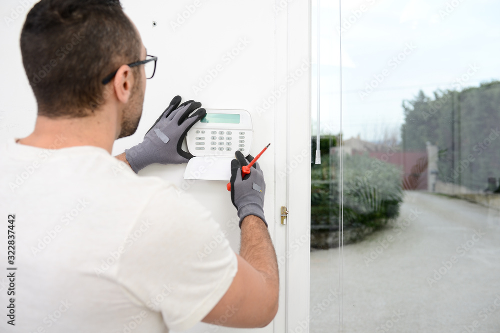 handsome man worker installing alarm technology insurance in home for burglar prevention - obrazy, fototapety, plakaty 