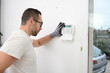 © W PRODUCTION - handsome man worker installing alarm technology insurance in home for burglar prevention
