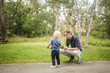 © Maskot - Father and son with toy car on footpath against plants at park