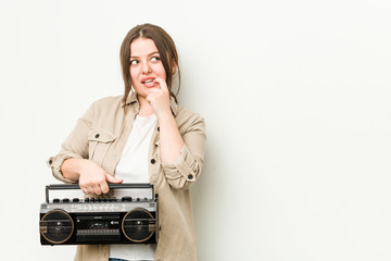 Wall Mural - Young curvy woman holding a retro radio relaxed thinking about something looking at a copy space.