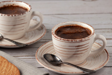 Two cups of aromatic coffee on an old white wooden table.