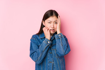 Wall Mural - Young chinese woman posing in a pink background isolated whining and crying disconsolately.