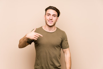 Wall Mural - Young caucasian man posing isolated person pointing by hand to a shirt copy space, proud and confident