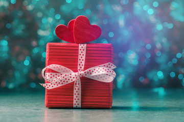 Two red hearts on gift box against holiday defocused lights. Valentines day concept