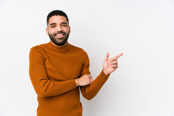 Wall Mural - Young latin man against a white background isolated smiling cheerfully pointing with forefinger away.