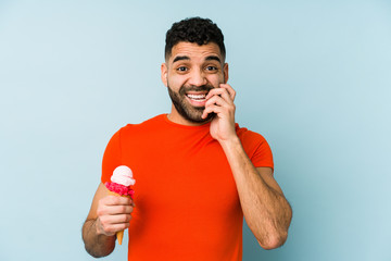 Wall Mural - Young latin man holding an ice cream isolated biting fingernails, nervous and very anxious.