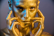 © de Art - woman golden skin face in bright sparkles, Trendy glowing gold skin make-up. Glitter metallic shine makeup