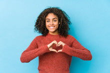 Young African American Curly Hair Woman Smiling And Showing A Heart Shape With Hands.