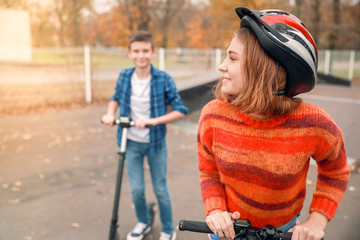 Active teenagers riding kick scooters in skate park