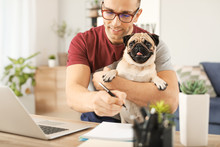 Handsome Man With Cute Pug Dog And Laptop At Home
