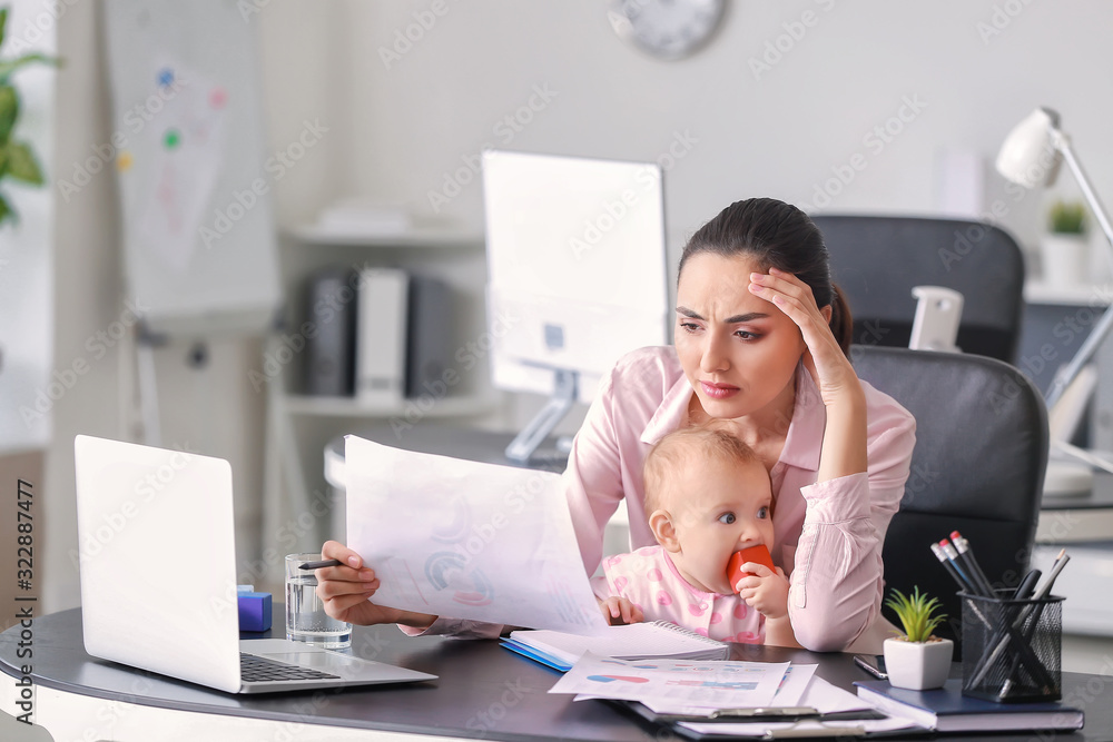 Stressed mother with her baby working in office