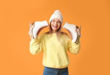 Wall Mural - Beautiful young woman with ice skates on color background