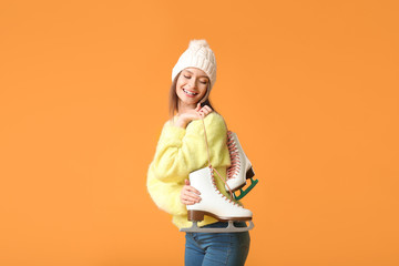 Wall Mural - Beautiful young woman with ice skates on color background